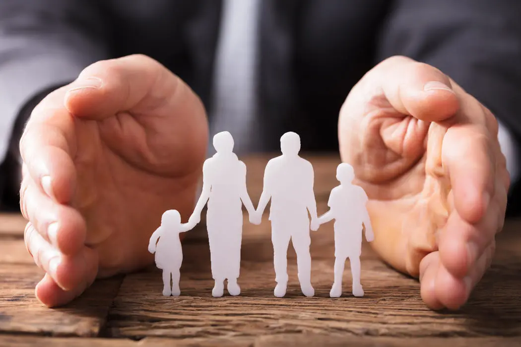 A paper cut out of a family with hands around them to represent safeguarding