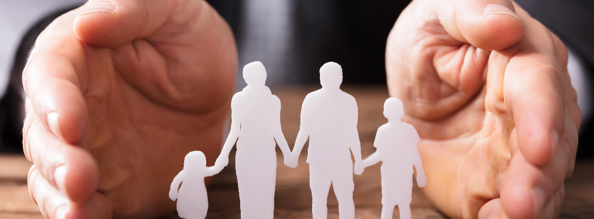 A paper cut out of a family with hands around them to represent safeguarding