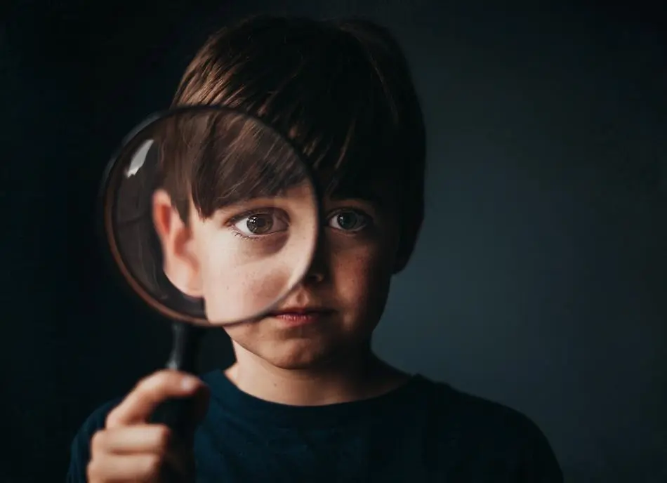 Image of a little boy looking through a magnifying glass