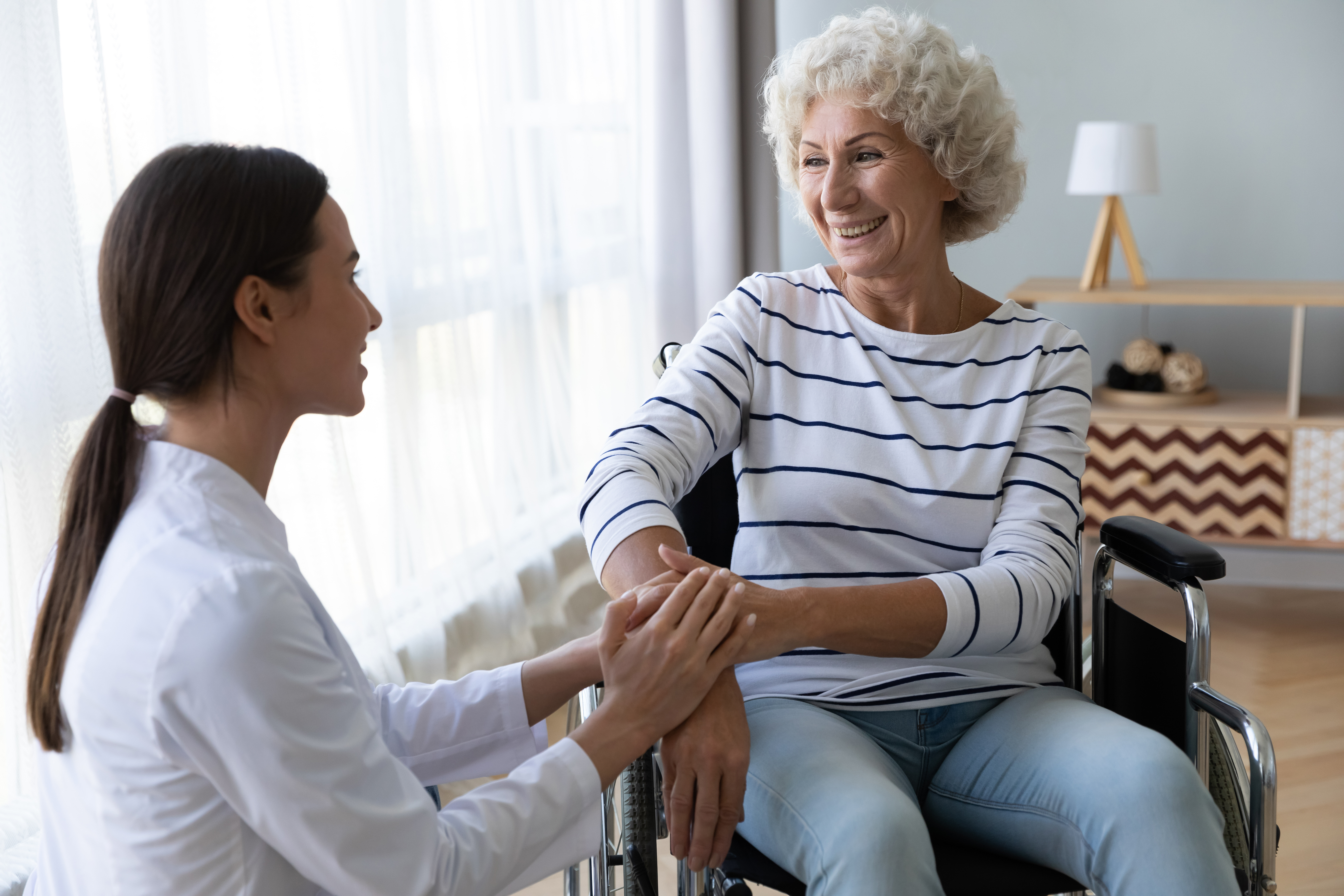 Elderly lady in a wheelchair chatting with a relative