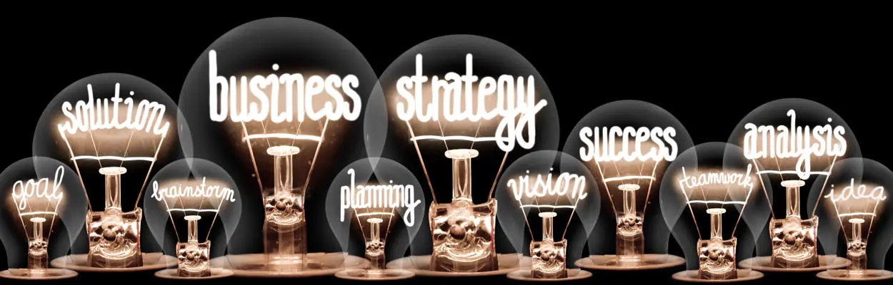 Photo of shining light bulbs with words related to Business Strategy inside them
