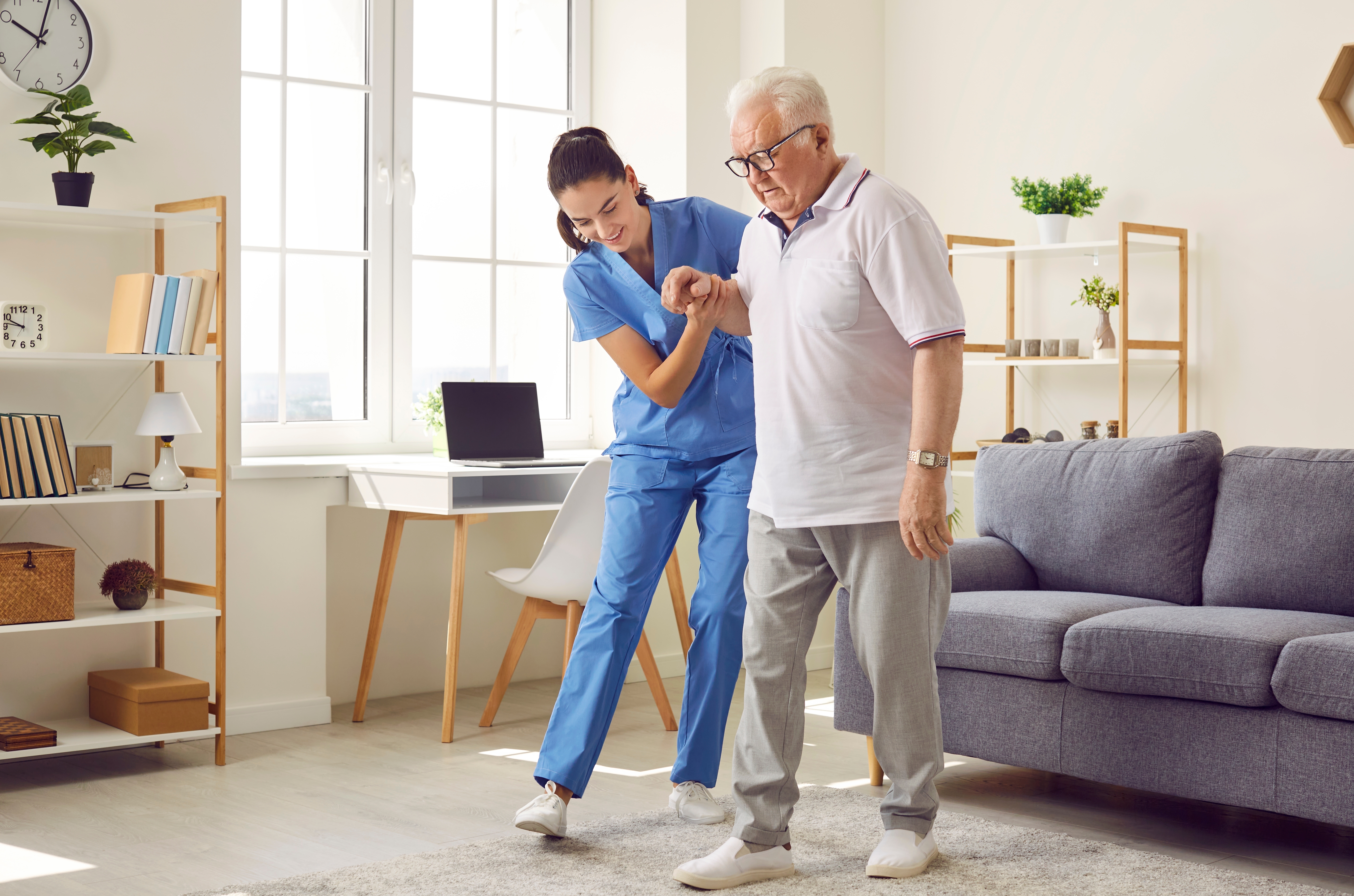 Care worker assisting an elderly man to walk