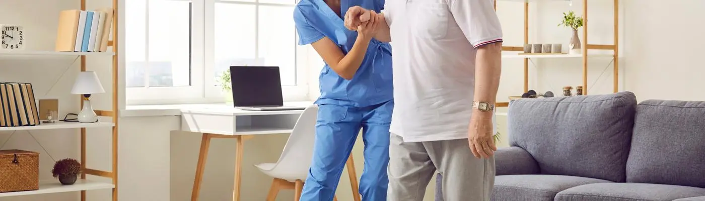 Care worker assisting an elderly man to walk