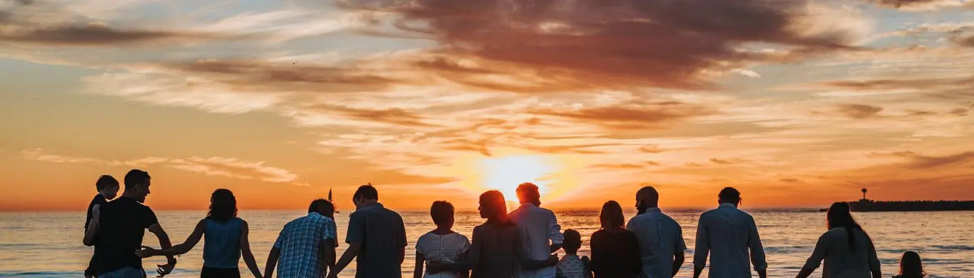 A group of people of all ages watching the sunset by the sea